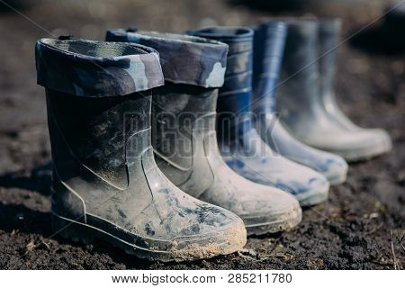 Variety Of Rubber Boots In A Line In The Dirt In Early Spring