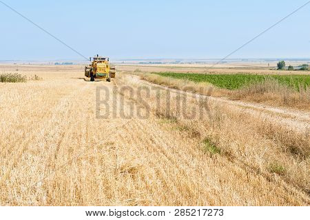 Harvester In The Foreground On Rustic Background Working In The Field