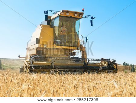 Harvester In The Foreground On Rustic Background Working In The Field