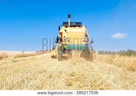 Harvester In The Foreground On Rustic Background Working In The Field