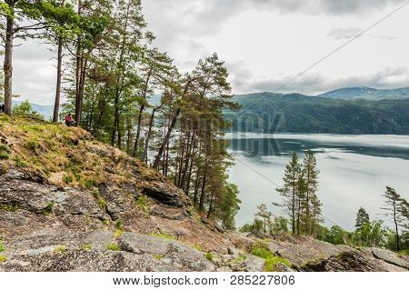 Female Tourist Enjoying Fjord View Ysaudafjord On Overcast Weather, View From Svandalsfossen Waterfa
