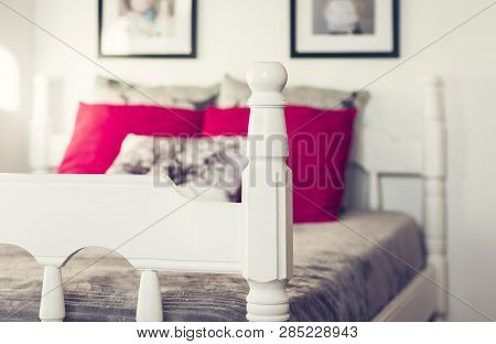 White Wooden Carved Bed With Gray Bedspread And Red Pillows