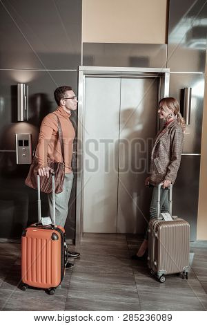 Stylish Couple Standing Near Elevator With Their Luggage