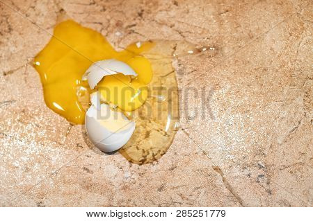 The Egg Is Broken On A Stone Marble Floor. Front Focus