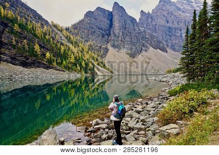 Hiker In Front Of Reflective Lake Agnes