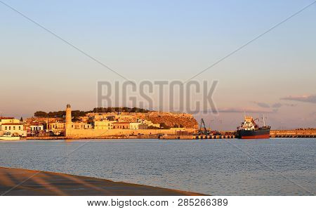 A Beautiful View Of Harbour In Rethymno With Lighthouse And Fortress Fortezza At Sunrise, Crete Isla