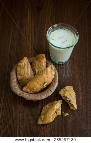 Glass of flavoued milk and Gujiya - a traditional Indian sweet and beverage which is relished on the occasion of Holi Festival.