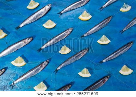 Fish Pattern. Anchovies In The Shape Of A Circle On A Black Stone On A Blue Sea Background. Seafood.