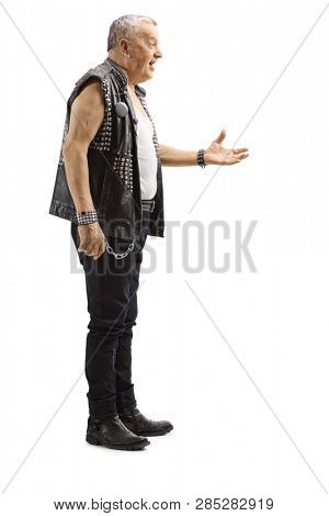 Full length profile shot of a mature male punker in a leather vest gesturing with hand isolated on white background