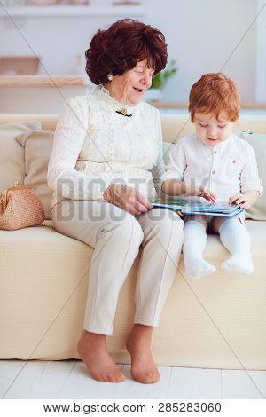 Portrait Of Beautiful Mature Woman (80 Years Old) With Her Great-grandson At Home, Reading Education