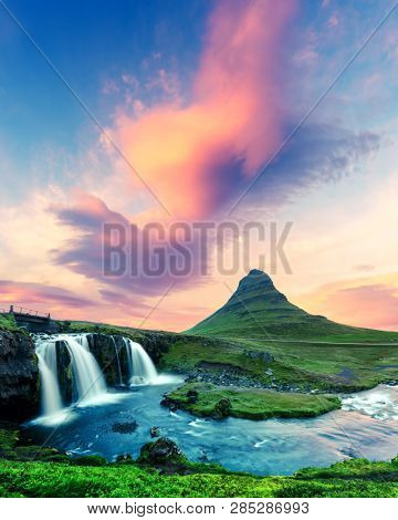 Colorful sunrise on Kirkjufellsfoss waterfall. Amazing morning scene near Kirkjufell volkano, Iceland