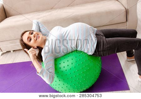 Young pregnant woman doing sport exercises at home 