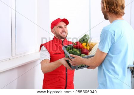 Courier Giving Plastic Crate With Products To Customer At Home. Food Delivery Service