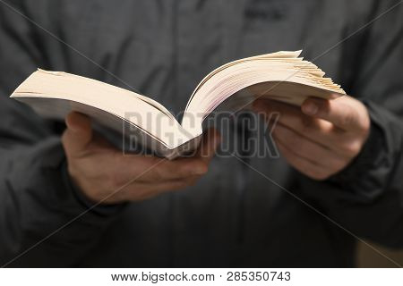 Detail Of Man Reading A Book With Dogears Bookmarks.