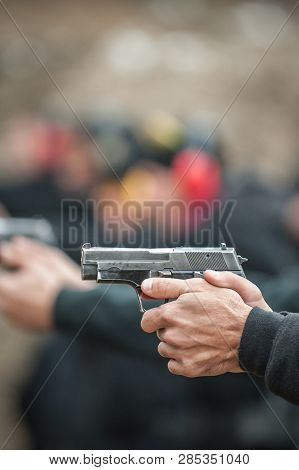 Close-up Detail View Of Shooter Hold Handgun In Row Group Of People On The Shooting Range