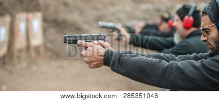 Close-up Detail View Of Shooter Hold Handgun In Row Group Of People On The Shooting Range