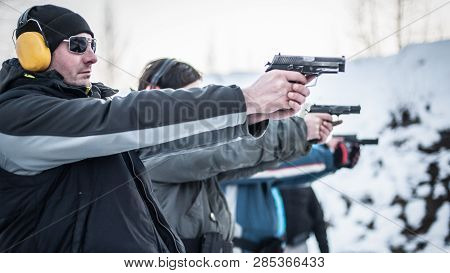 Close-up Detail View Of Shooter Hold Handgun In Row Group Of People On The Shooting Range