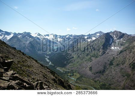 Scenic Mountain Landscape. Mountain Snow-capped Peaks. River Flowing Through A Canyon Between Two Mo