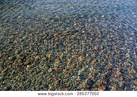 Blue Lake Idill Under Cloudline Sky. The Stones On The Shore Of The Lake And Background. The Stones 