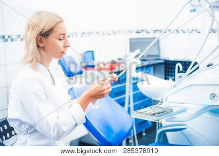 Dental doctor in white uniform working with equipment in stomathology office