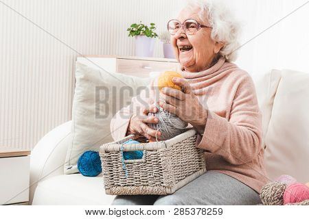 Smiling eldery woman with white basket holding colorful laces balls
