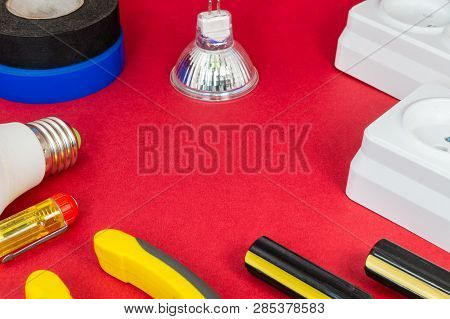 Tools And Accessories For The Electrician Bulbs, Sockets, Screwdrivers On A Red Background.
