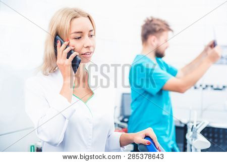 Dental doctor talking on smartphone in stomathology office