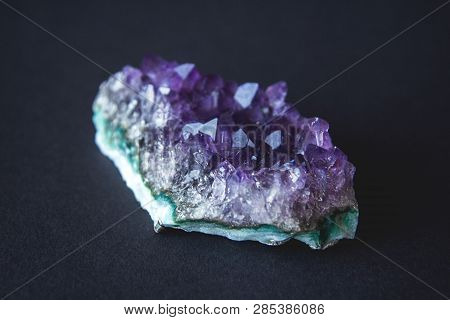 Close-up Of Amethyst Stone Druse Crystals On Dark Granite Polished Slab. Texture Of Crystals Of Amet