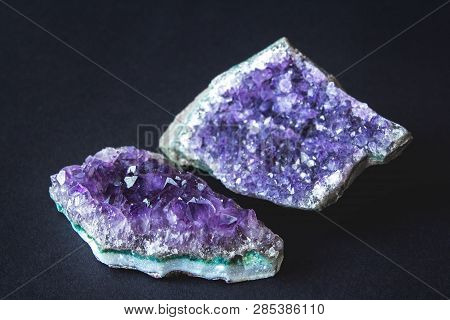 Close-up Of Amethyst Stone Druse Crystals On Dark Granite Polished Slab. Texture Of Crystals Of Amet