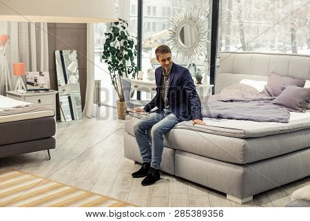 Good-appealing Beaming Man Resting On New Bed In Furniture Store