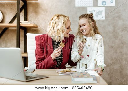 Joyful And Laughing Daughter With Her Mother Eating Tasty Chocolate Cookies