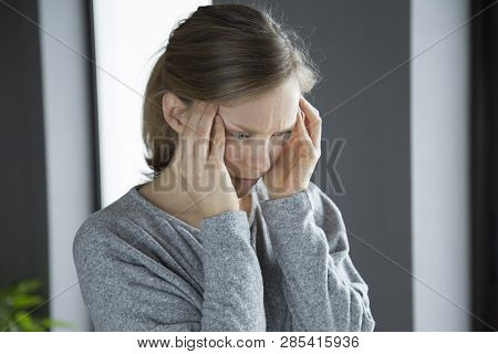 Sick Young Fair-haired Caucasian Woman At Home Massaging Temples, Touching Aching Head, Feeling Stro