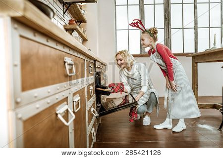 Short-haired Beaming Woman Using Special Glove For Putting Hot Pan