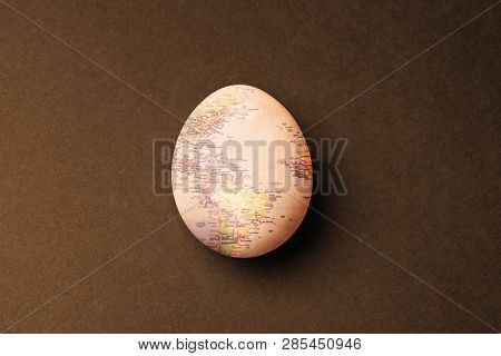 One Light Egg With World Map Pattern As A Globe With A Shadow On Contrast Brown Background With Roug