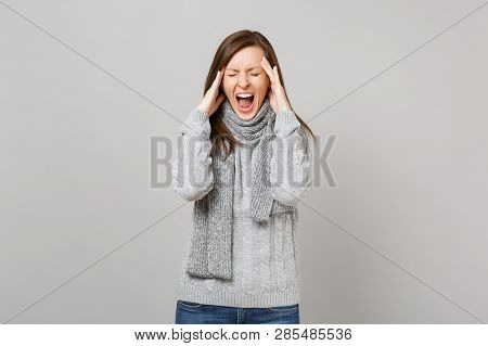 Jaded Young Woman In Gray Sweater, Scarf With Closed Eyes Screaming Putting Hands On Head Having Hea