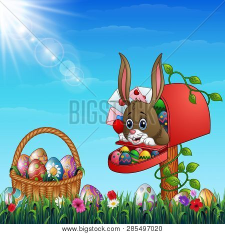Easter Bunny Out From Of The Mailbox With Easter Basket Full Of Decorated Easter Eggs In A Grass Fie