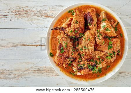 Chicken Stewed In Creamy Spicy Coconut Sauce, Kuku Paka, Served On A White Plate On An Old Wooden Ta