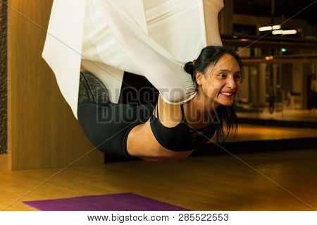 Young Woman Practicing Aerial Yoga In Fitness Studio