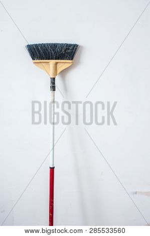 Close Up Of Red Black Broom On White Background. Cleanliness Concept. Copy Space.
