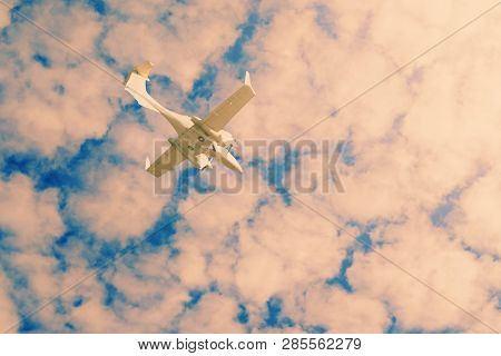 A Small Private White Plane With Screws Flies On The Background Sky With Clouds, Toned