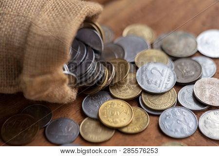 Indian Coins Spilling Out From A Burlap Sack On A Wooden Surface. Indian Currency Background Concept