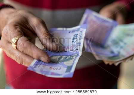 Indian Male Hand Giving Money Of One Hundred Rupees Note. Cash Giving Concept For Background.