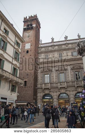 Italy, Verona - December 08 2017: The View Of Tourists On Piazza Delle Erbe With Torre Del Gardello 