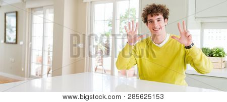 Wide angle shot of young handsome man at home showing and pointing up with fingers number eight while smiling confident and happy.
