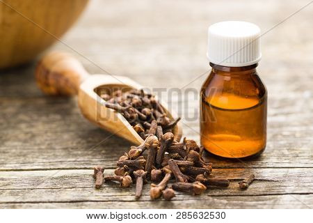 Essential oil of cloves and cloves spice on wooden table.
