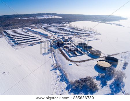 Aerial view to biogas plant from pig farm in snowy fields. Renewable energy from biomass. Winter on countryside. Modern agriculture in European Union. 