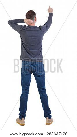 Back view of a man in jeans points his hand upwards. Rear view people collection.  backside view of person.  Isolated over white. The man in surprise pulls his head and points his finger forward.