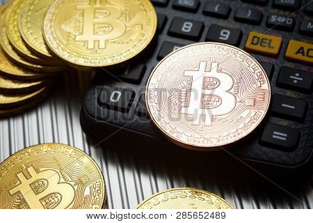 Bitcoins and calculator on a metal table.