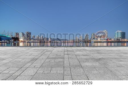 empty concrete square floor with skyline background at night, vancouver, canada.