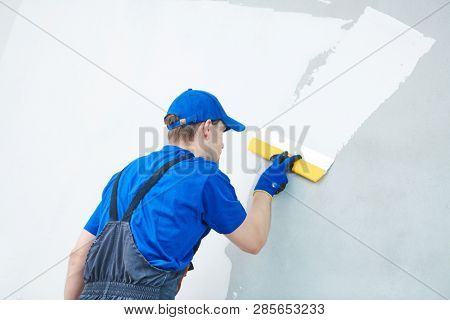 refurbishment. Plasterer worker spackling a wall with putty